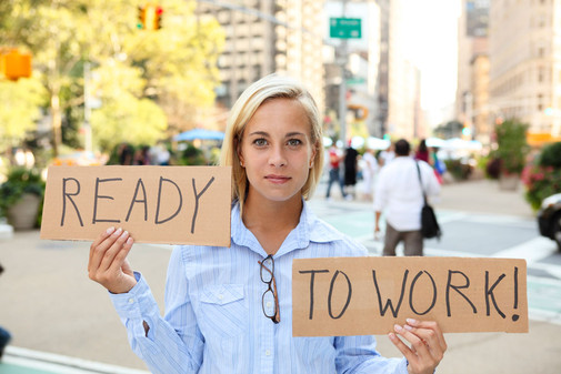 Junge Frau hält ein Schild mit der Aufschrift "Ready to Work!" hoch.