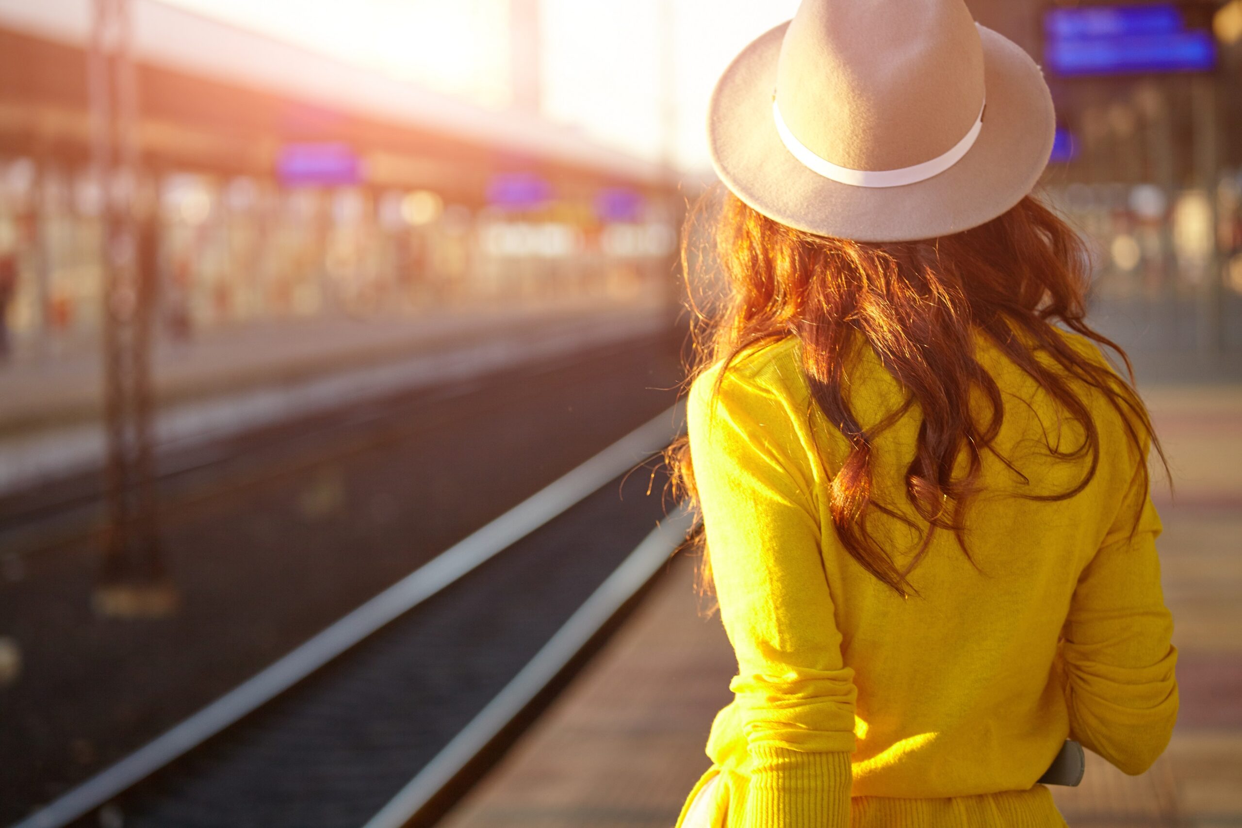 Studentin mit gelbem Kleid wartet am Bahnsteig